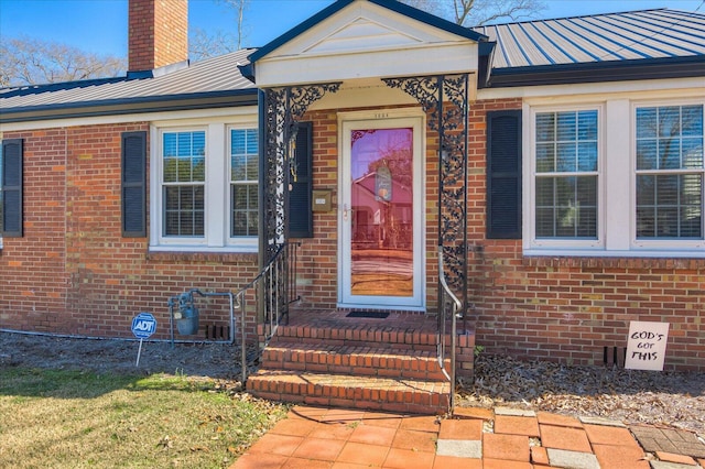 doorway to property featuring metal roof, brick siding, a chimney, and crawl space