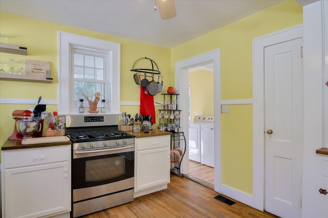 kitchen featuring washer and clothes dryer, light wood finished floors, visible vents, white cabinets, and gas range