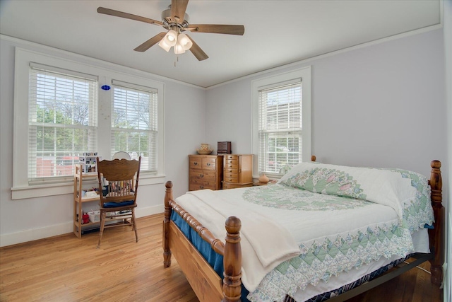 bedroom featuring baseboards, ornamental molding, multiple windows, and light wood-style floors