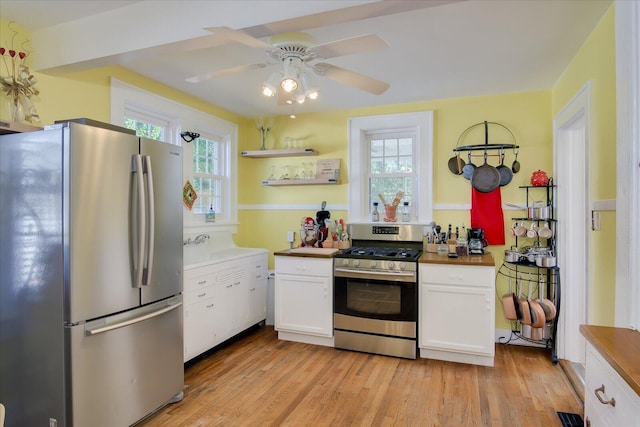 kitchen with appliances with stainless steel finishes, white cabinetry, ceiling fan, and light wood-style flooring