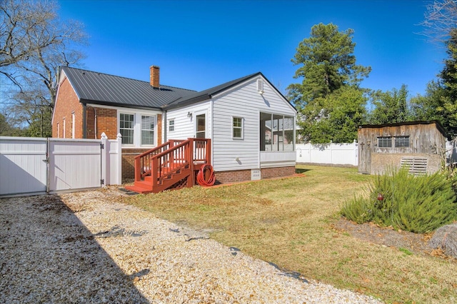 back of property featuring metal roof, fence, a yard, a gate, and a chimney