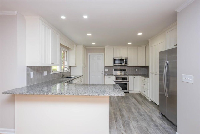 2924 Stratford Dr, Augusta, GA 30909 - kitchen featuring stainless steel appliances, a peninsula, backsplash, light wood-style floors, and light stone countertops