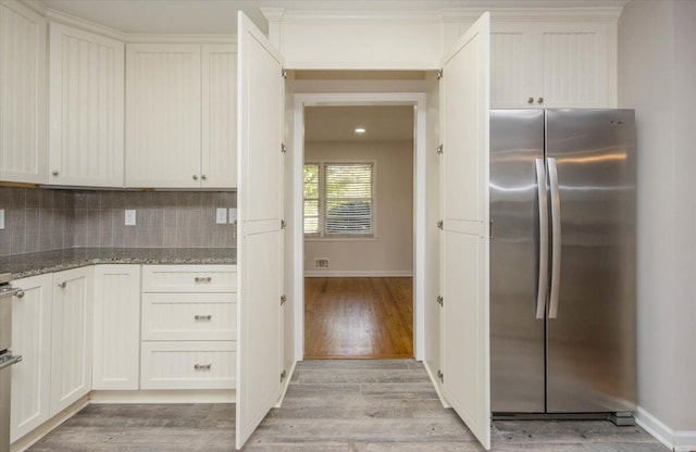 2924 Stratford Dr, Augusta, GA 30909 - kitchen featuring freestanding refrigerator, light stone countertops, light wood-type flooring, backsplash, and white cabinetry