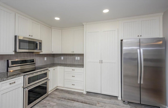 2924 Stratford Dr, Augusta, GA 30909 - kitchen featuring stainless steel appliances, light wood-style flooring, dark stone countertops, decorative backsplash, and white cabinets