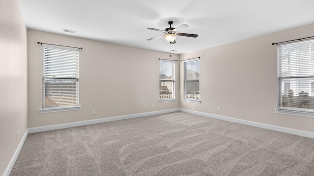 carpeted spare room with ceiling fan and plenty of natural light