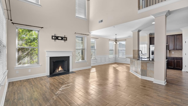 unfurnished living room featuring ornamental molding, a high ceiling, and sink