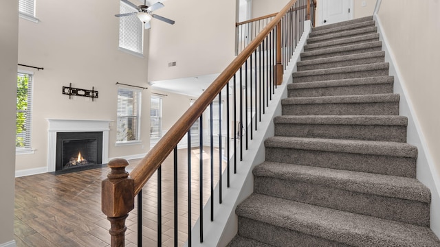 stairs featuring a high ceiling, ceiling fan, and hardwood / wood-style flooring