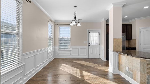 unfurnished dining area with an inviting chandelier, crown molding, and a healthy amount of sunlight