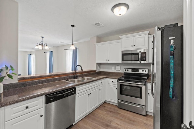 3382 Grove Landing Cir, Grovetown, GA 30813 - kitchen featuring appliances with stainless steel finishes, white cabinetry, dark countertops, a chandelier, and hanging light fixtures