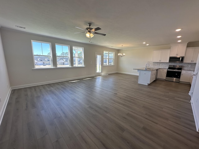 kitchen with dark wood finished floors, tasteful backsplash, open floor plan, and appliances with stainless steel finishes