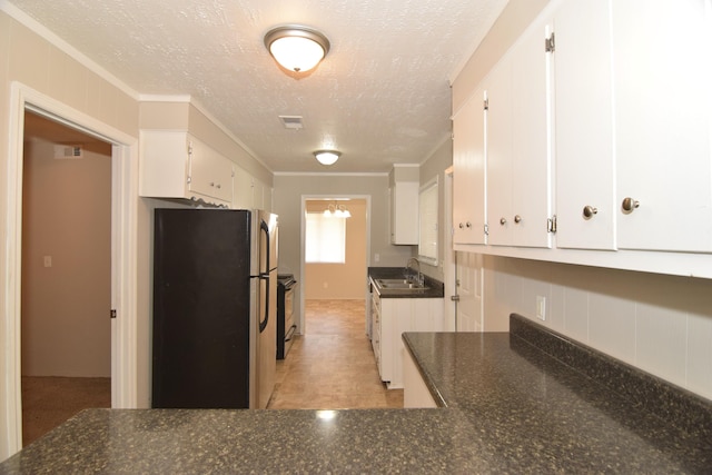 kitchen featuring crown molding, white cabinetry, a sink, and freestanding refrigerator