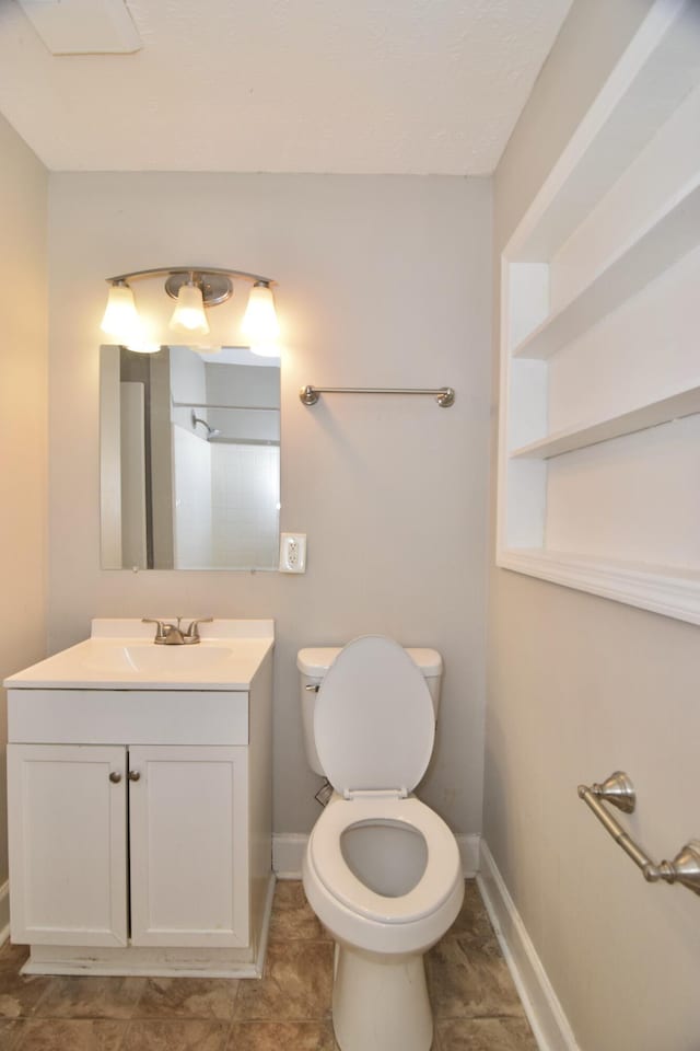 bathroom featuring baseboards, vanity, and toilet