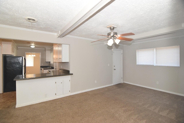 kitchen featuring dark countertops, freestanding refrigerator, white cabinets, carpet flooring, and a textured ceiling