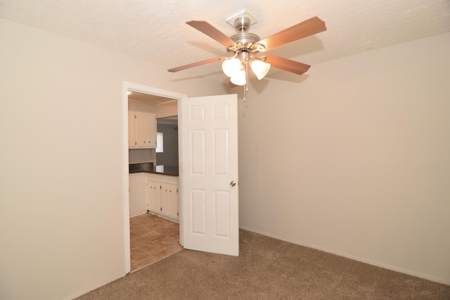 unfurnished room with light carpet, a textured ceiling, and a ceiling fan