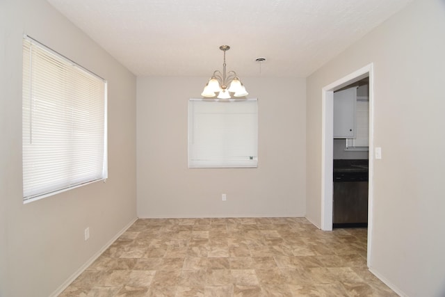 empty room with a chandelier and baseboards