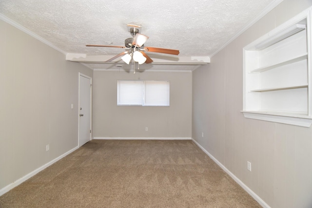 carpeted empty room featuring a textured ceiling, ornamental molding, a ceiling fan, and baseboards