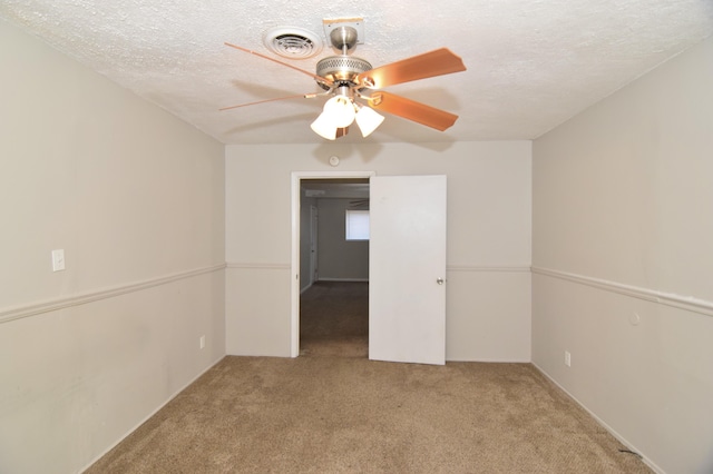 carpeted empty room with a textured ceiling, ceiling fan, and visible vents