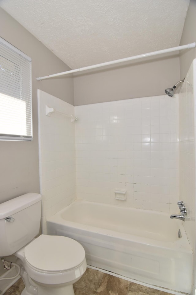 full bath with  shower combination, tile patterned flooring, a textured ceiling, and toilet