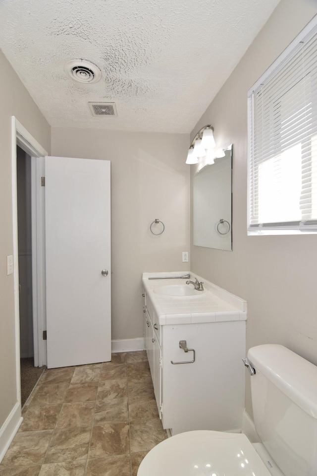 bathroom featuring toilet, visible vents, a textured ceiling, and vanity