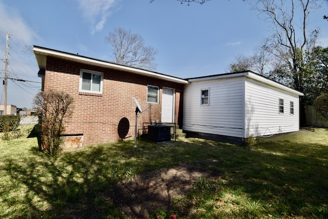 rear view of house with central air condition unit, a yard, fence, and brick siding