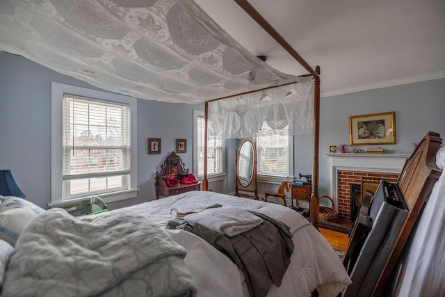 bedroom featuring crown molding, a fireplace, multiple windows, and hardwood / wood-style flooring