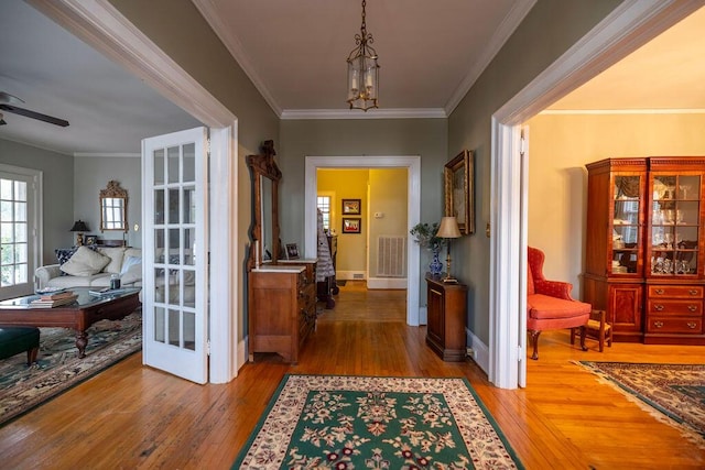 corridor with hardwood / wood-style floors, ornamental molding, and french doors