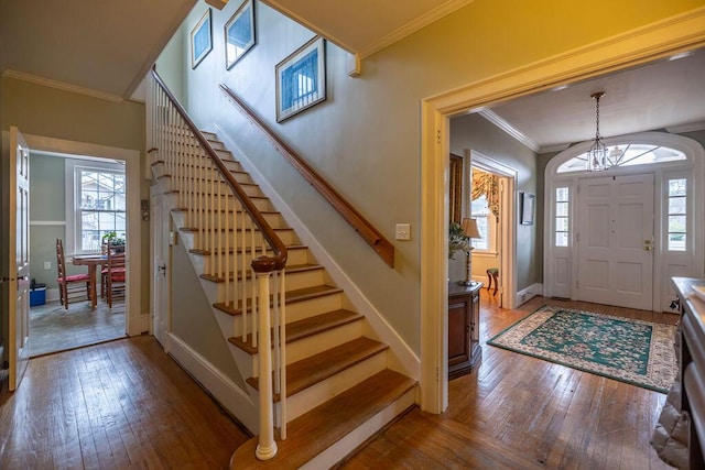 entryway with an inviting chandelier, crown molding, and hardwood / wood-style flooring