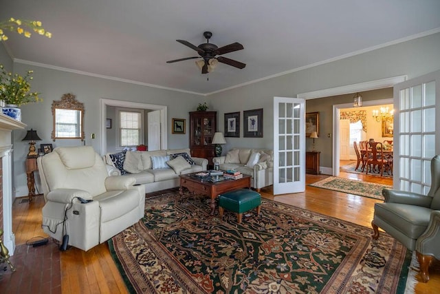 living room with ceiling fan with notable chandelier, wood-type flooring, ornamental molding, and french doors