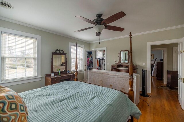 bedroom featuring hardwood / wood-style flooring, ceiling fan, ornamental molding, and multiple windows