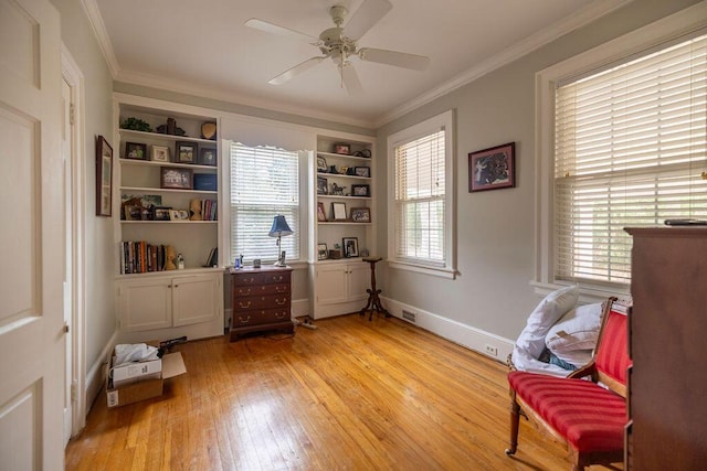 living area with ornamental molding, ceiling fan, light hardwood / wood-style floors, and built in shelves