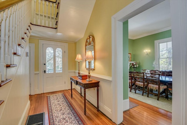 entrance foyer with ornamental molding and light hardwood / wood-style flooring