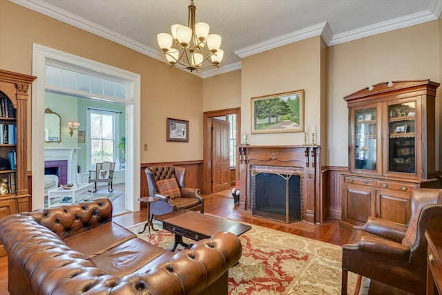 living room with light hardwood / wood-style flooring, a fireplace, ornamental molding, and an inviting chandelier