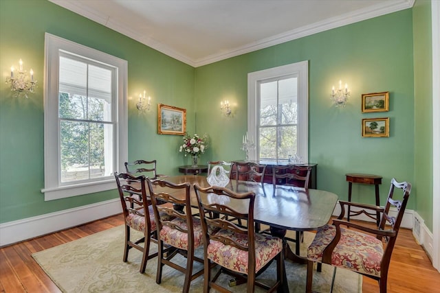 dining room with crown molding, light hardwood / wood-style floors, and a healthy amount of sunlight