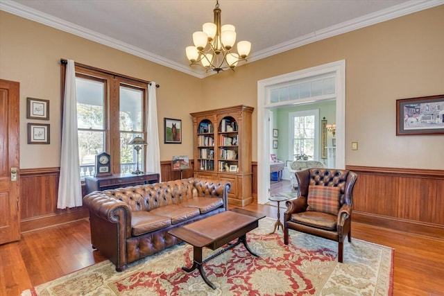 living room featuring an inviting chandelier, crown molding, plenty of natural light, and light hardwood / wood-style floors