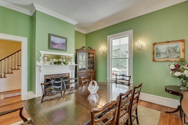 dining space featuring hardwood / wood-style floors, crown molding, and a fireplace