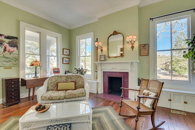 living area with crown molding, a brick fireplace, and hardwood / wood-style flooring