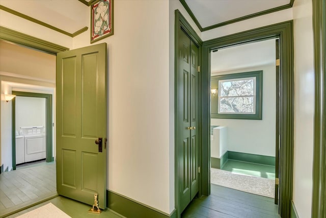 corridor featuring crown molding, wood-type flooring, and separate washer and dryer