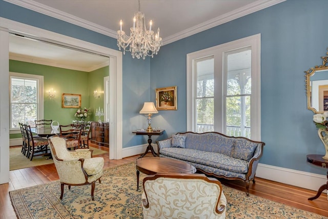 living area featuring crown molding, an inviting chandelier, and light wood-type flooring