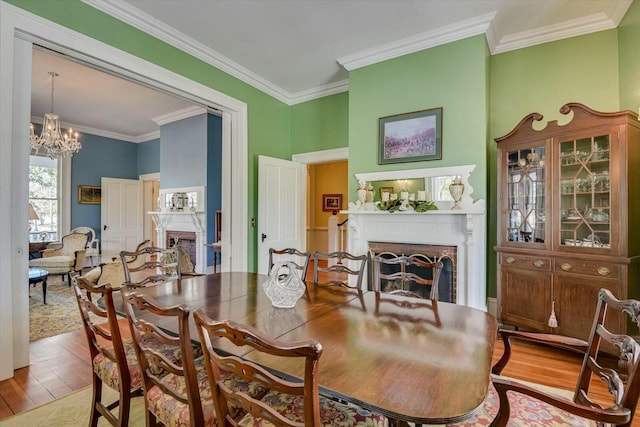 dining space with hardwood / wood-style floors, a fireplace, ornamental molding, and a chandelier