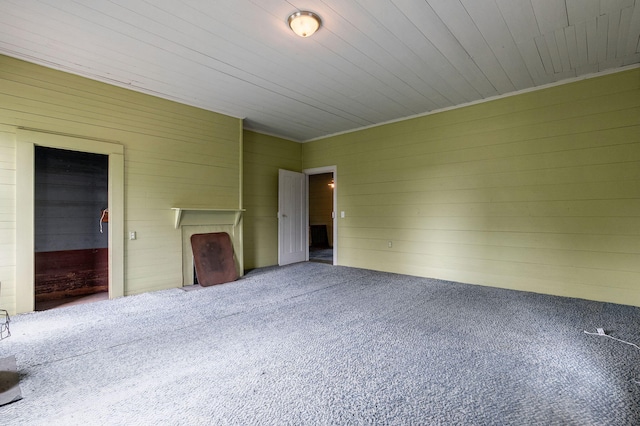 unfurnished bedroom featuring wood walls, carpet, and wooden ceiling