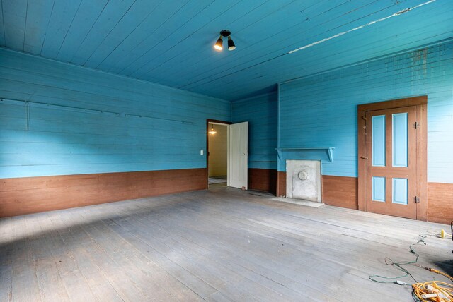 empty room with hardwood / wood-style flooring and wooden walls