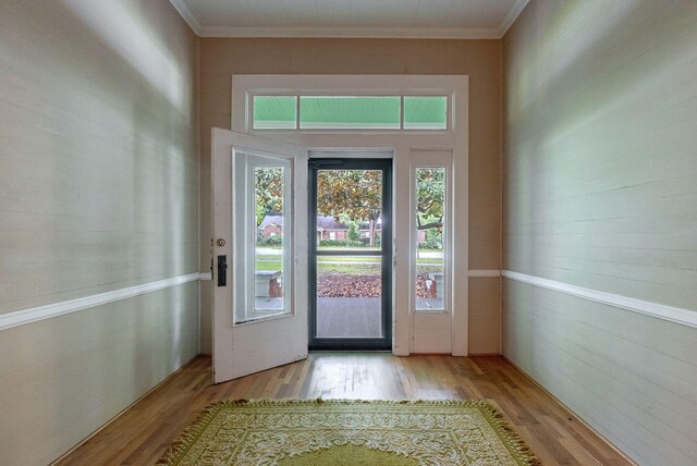 entryway with ornamental molding and light wood-type flooring