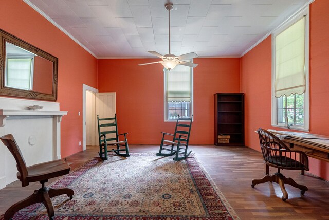 living area featuring ceiling fan, wood-type flooring, and crown molding