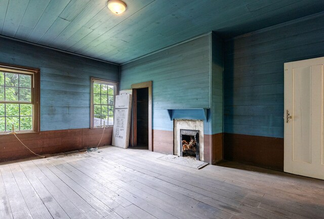 unfurnished living room featuring light hardwood / wood-style flooring, a high end fireplace, and wooden ceiling