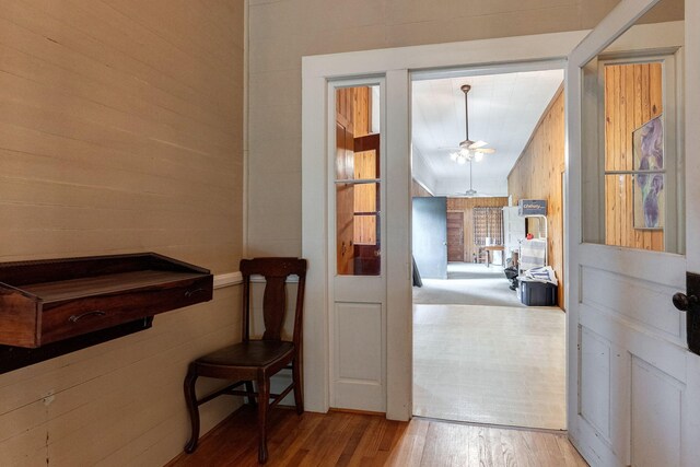 hallway with light hardwood / wood-style floors and wooden walls