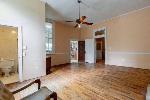 unfurnished living room featuring ceiling fan, hardwood / wood-style floors, and a towering ceiling