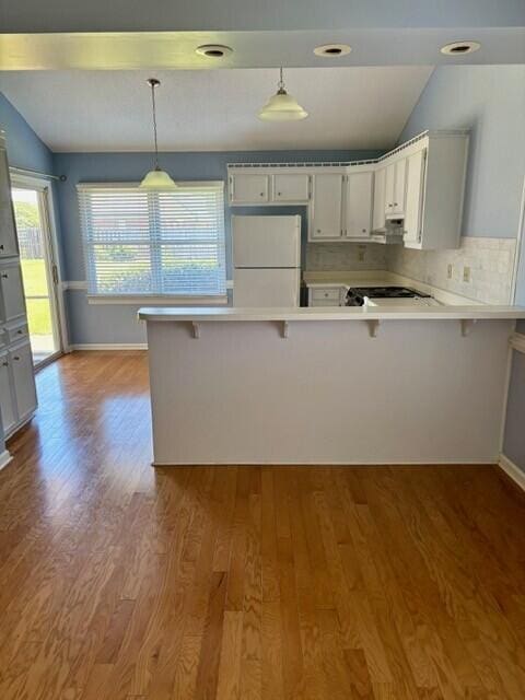 2949 Hillcreek Dr, Augusta, GA 30909 - kitchen with freestanding refrigerator, a peninsula, wood finished floors, light countertops, and lofted ceiling