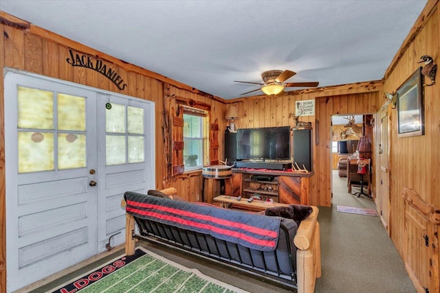 living room with ceiling fan, carpet, and wood walls