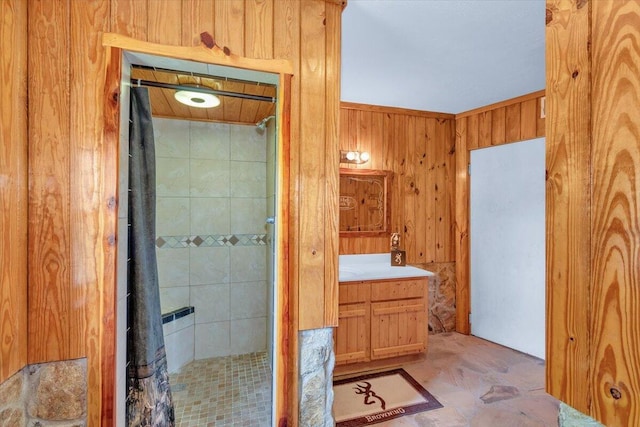 bathroom featuring vanity, wood walls, and tiled shower