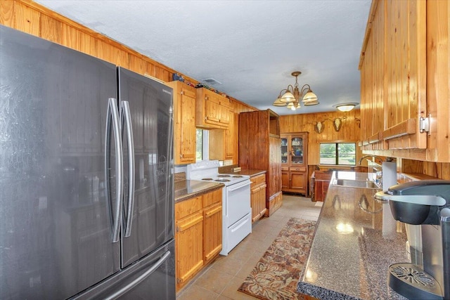 kitchen with decorative light fixtures, wooden walls, fridge, a notable chandelier, and white electric range oven